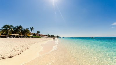 Sunny day on Seven Mile Beach, Grand Cayman, with clear turquoise water and palm trees