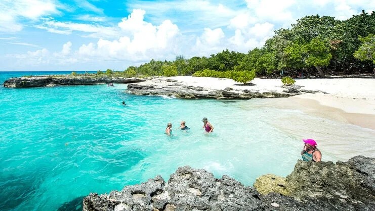 Families wading and snorkeling in the shallow protected cove at Smith Cove, Grand Cayman