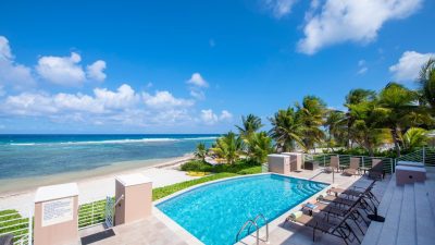 A beachfront villa private pool overlooking the ocean in Grand Cayman, the kind of layout that suits a multigenerational family trip