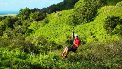 Teen ziplining through lush green hillside in West Maui