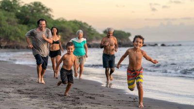Multiple generations of a family running together on a beach