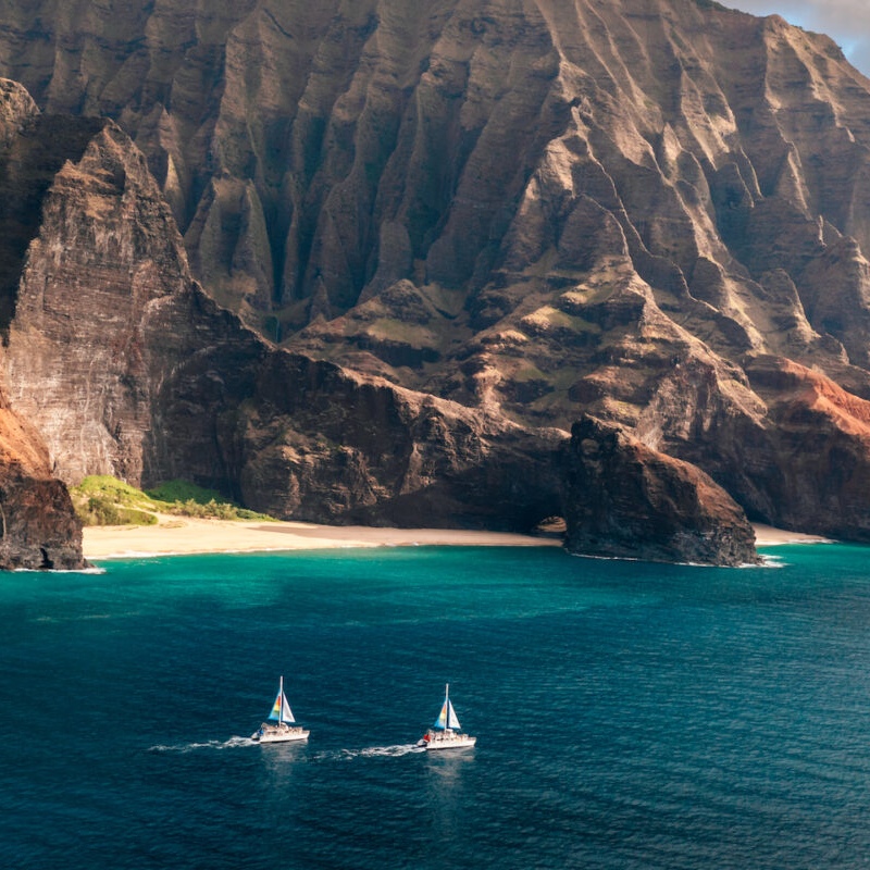 Catamaran boats along Na Pali Coast cliffs Kauai