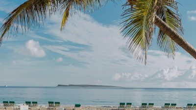 Calm beach with palm trees and loungers at Orient Bay, St Martin, under a clear sky
