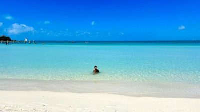 Calm, shallow turquoise water at Sapodilla Bay Beach, Providenciales, with someone wading